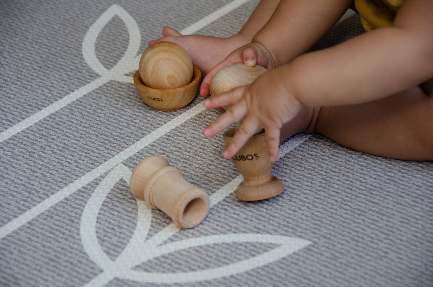 Baby joyfully playing with the Egg Cup from the Cubos Ball Bowl Peg & Egg Cup set, discovering the fun and surprises it offers during playtime.