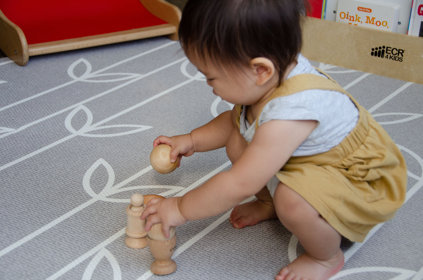 Enthusiastic baby fully engaged in play, using both hands to explore and interact with the Cubos Ball Bowl, Peg & Egg Cup set, enjoying the multi-sensory experience.