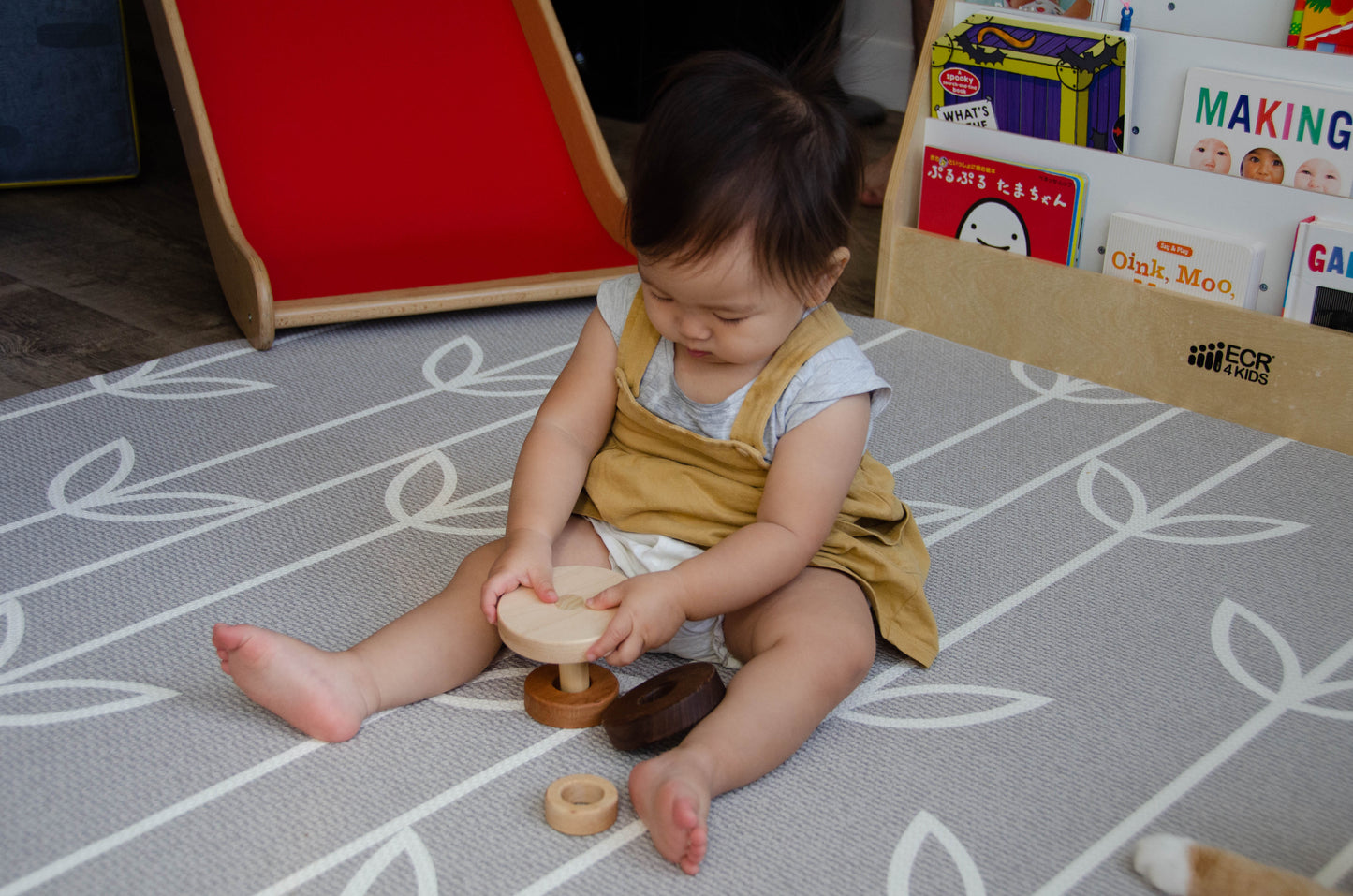 Adventurous baby creatively stacks the Cubos 3 Different Size Rings Stacker upside down, showcasing their curiosity and imagination.