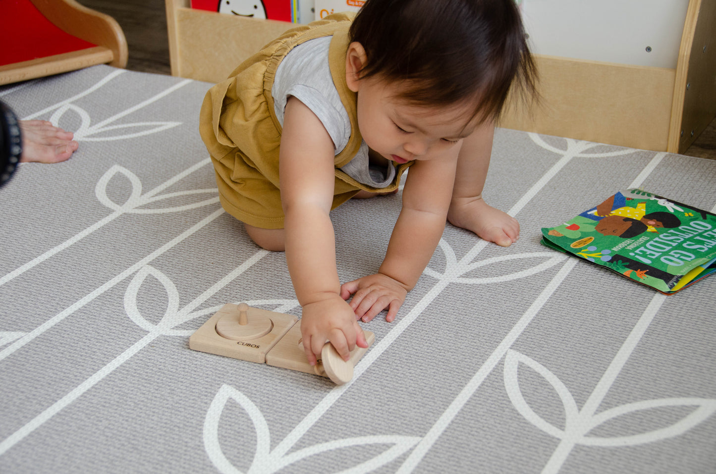 Adorable baby reaching out to grasp one of the circle puzzles from the Cubos 2 Different Size Circle Puzzle, eager to explore and play with the intriguing wooden toy.