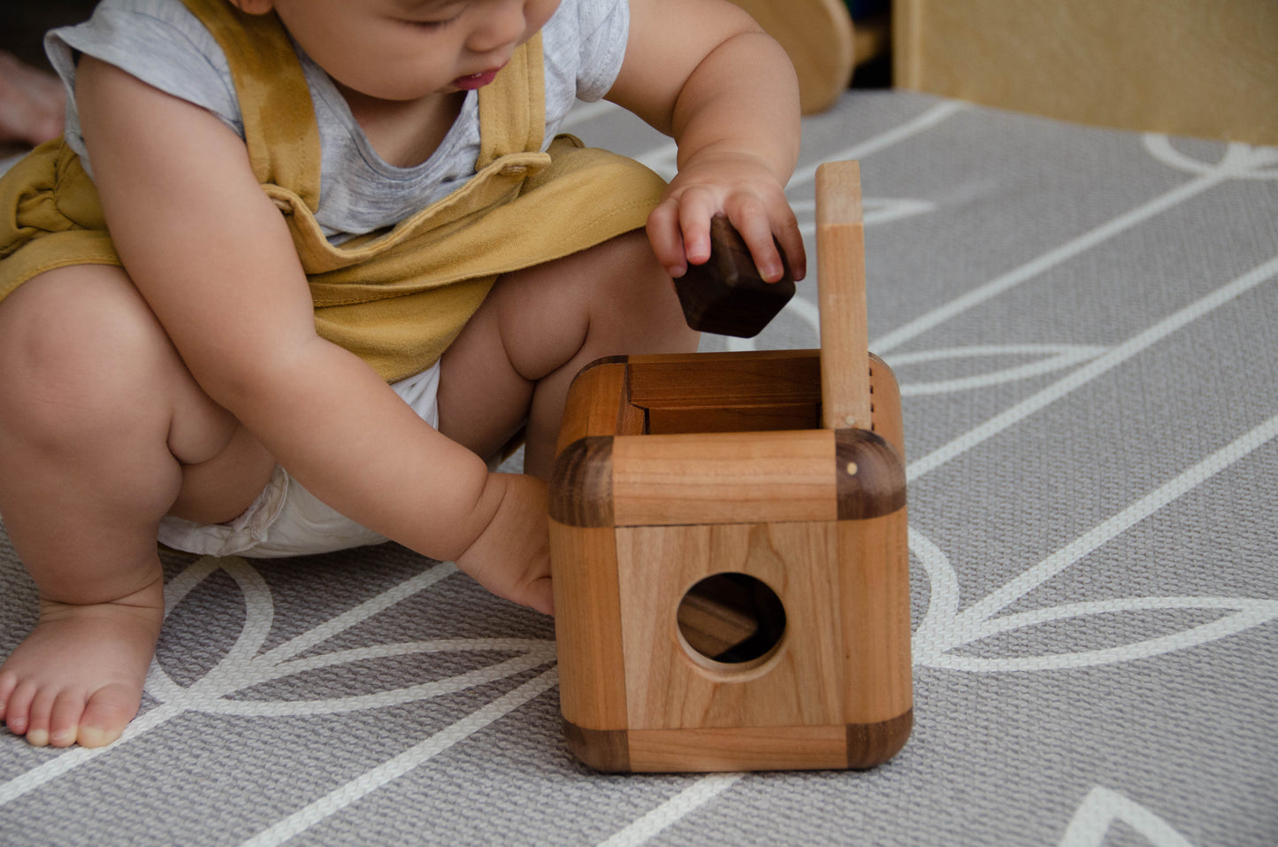Endearing baby girl carefully putting back the insert pieces into the Cubos Lite, demonstrating her focus and fine motor skills as she tidies up after playtime.