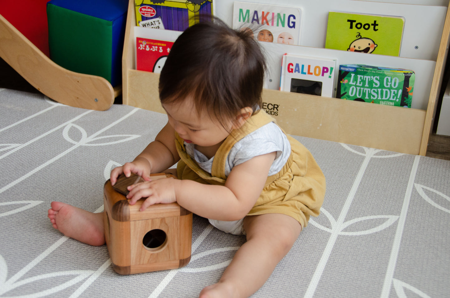 Baby girl gleefully placing the square insert into the Cubos Lite, mastering the art of spatial manipulation and enjoying the satisfying engagement with the interactive toy.