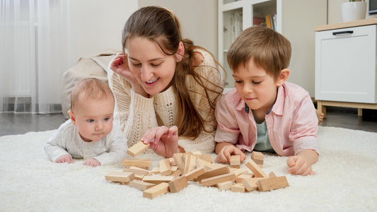 A mother happily playing with wooden toys alongside her two children, engaging in a joyful and educational activity together.