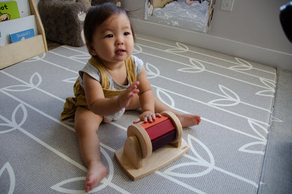 The little girl is joyfully playing with a spinning wheel toy. With excitement and wonder, she spins the wheel, watching it whirl around and captivated by its motion. This interactive playtime engages her senses and fosters her fine motor skills as she explores the spinning action and its effects. Her imaginative play with the spinning wheel sparks curiosity and creativity, making playtime a delightful and enriching experience for her.