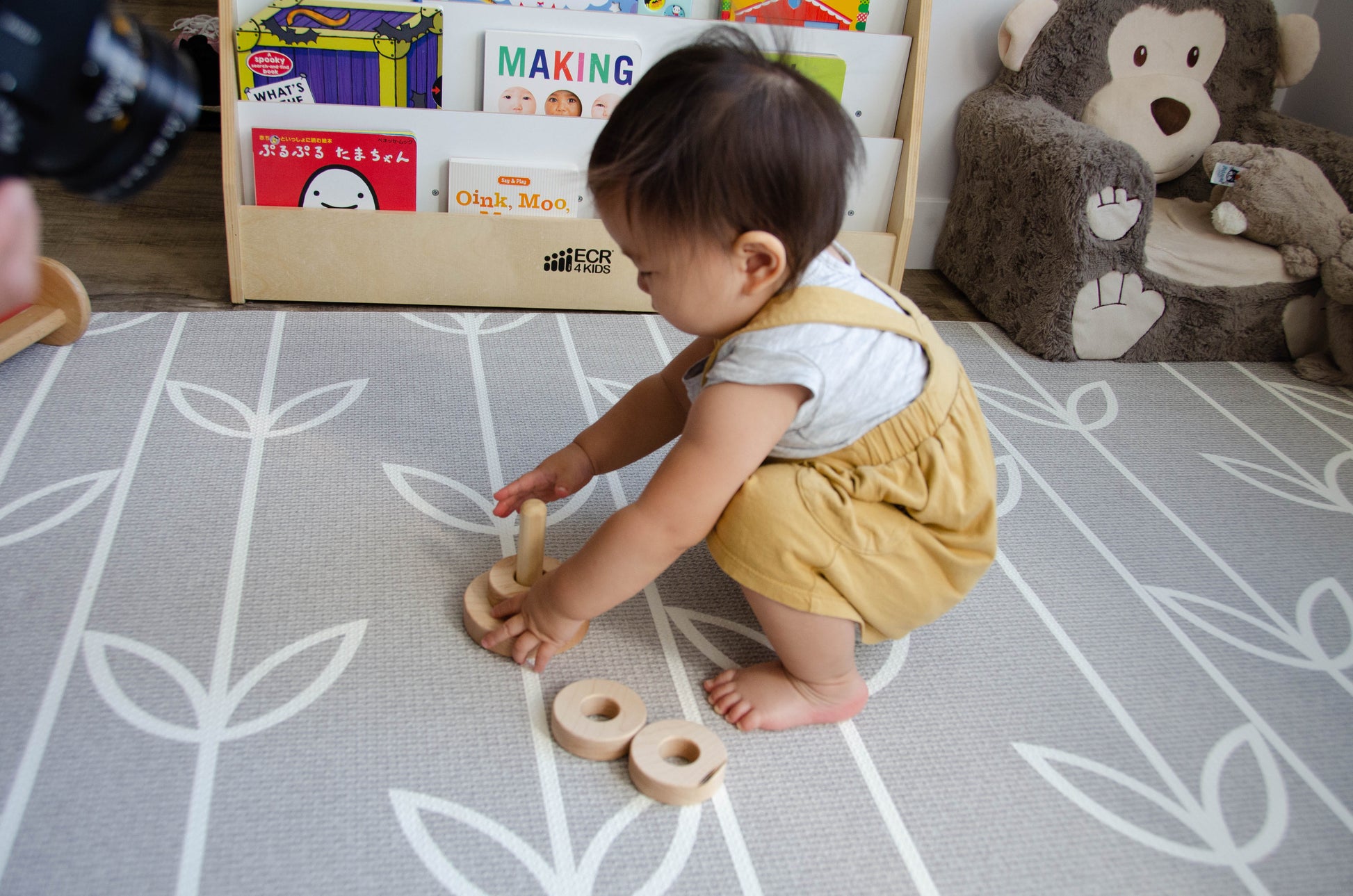 Adorable baby girl carefully placing the first ring on the Vertical Dowel, focusing her attention and honing her fine motor skills as she engages in delightful playtime exploration.