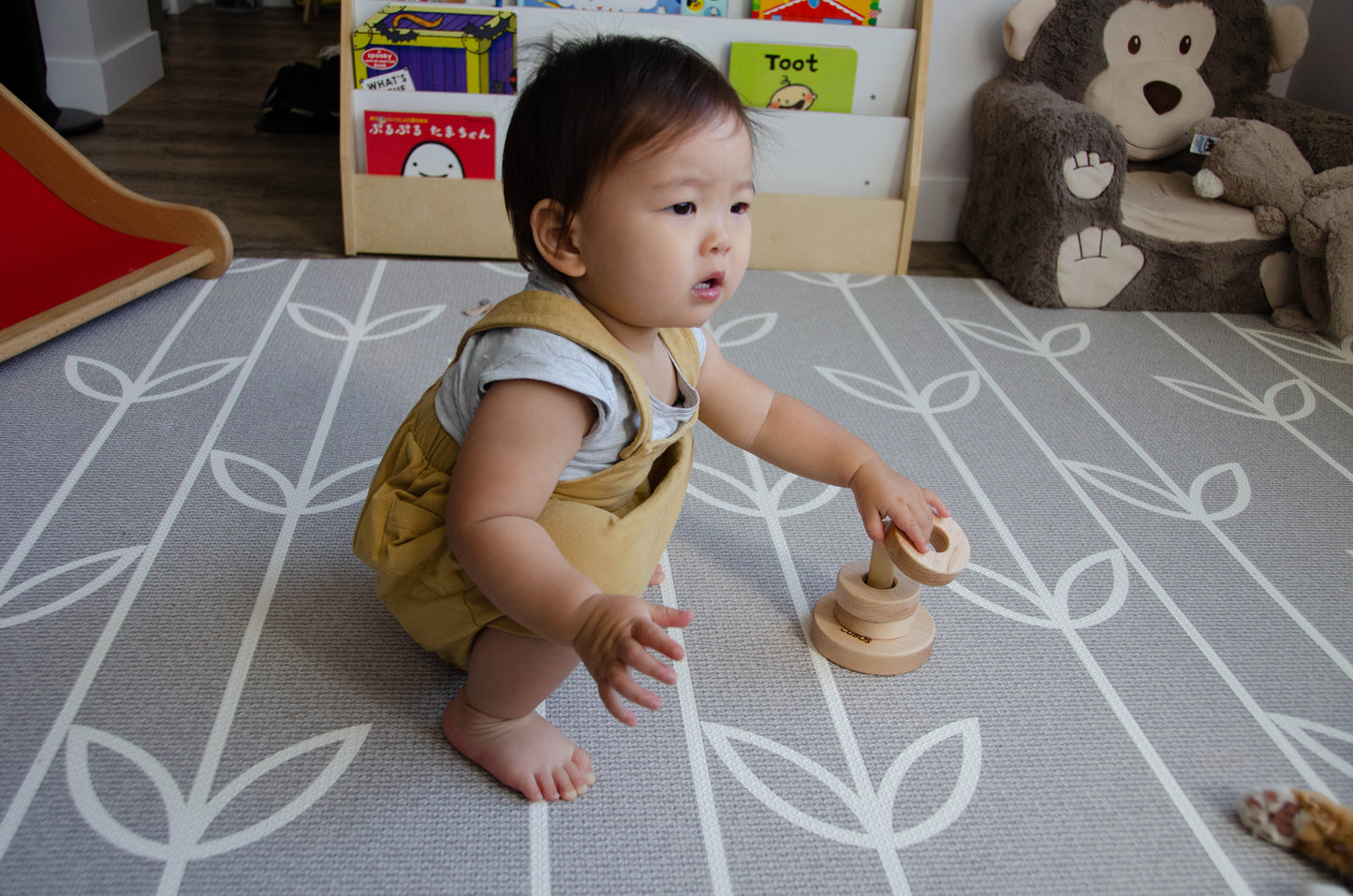 Brilliant baby girl skillfully putting the third ring on the Vertical Dowel, showcasing her growing mastery and confidence in stacking the rings. Her successful playtime endeavor demonstrates her developing motor skills and spatial understanding, making her playtime all the more enjoyable and enriching.
