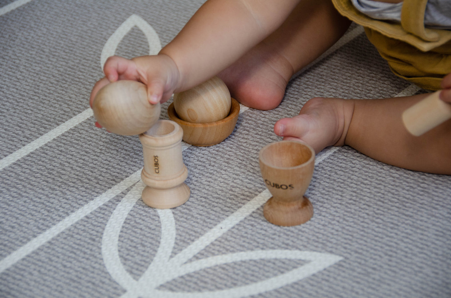 Baby joyfully playing with the Egg Cup from the Cubos Ball Bowl Peg & Egg Cup set, discovering the fun and surprises it offers during playtime.