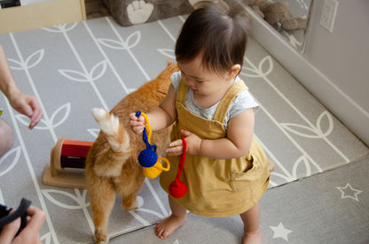Adorable baby girl playing with yarn balls alongside her kitty, creating a heartwarming scene of joy and companionship during their delightful playtime.