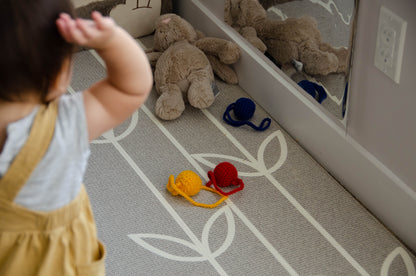 Playful baby girl gleefully throwing yarn balls, laughing with excitement and delight as she engages in a fun and lively playtime activity.