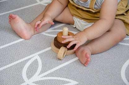Baby playfully stacks 2 out of 3 rings on the Cubos 3 Different Size Rings Stacker.