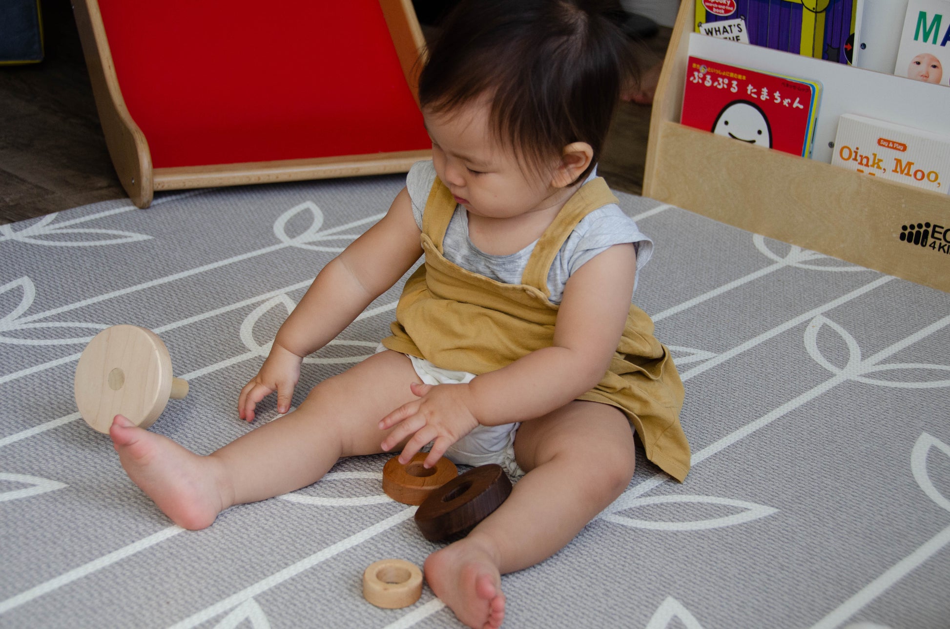 Joyful baby exploring the base of the Cubos 3 Different Size Rings Stacker during playtime.