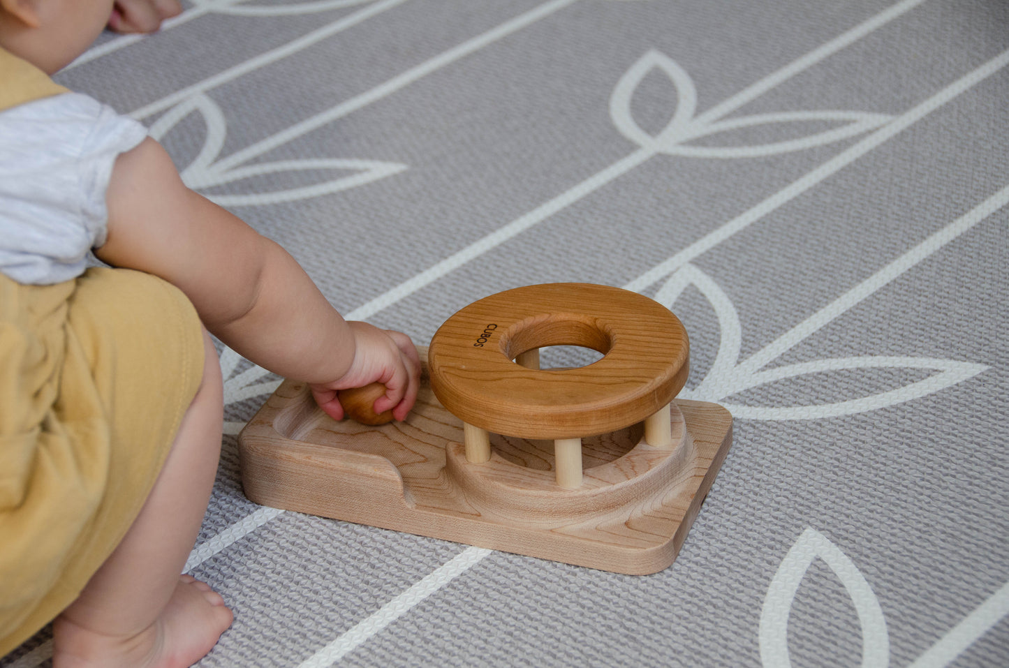 The baby girl is engrossed in play with the Permanence Box, a classic Montessori toy. With great curiosity and excitement, she explores the various compartments, practicing her hand-eye coordination and fine motor skills as she discovers the joy of fitting objects into their designated spaces. This educational and interactive playtime experience helps her develop an understanding of object permanence and spatial relationships, providing a foundation for her cognitive development.