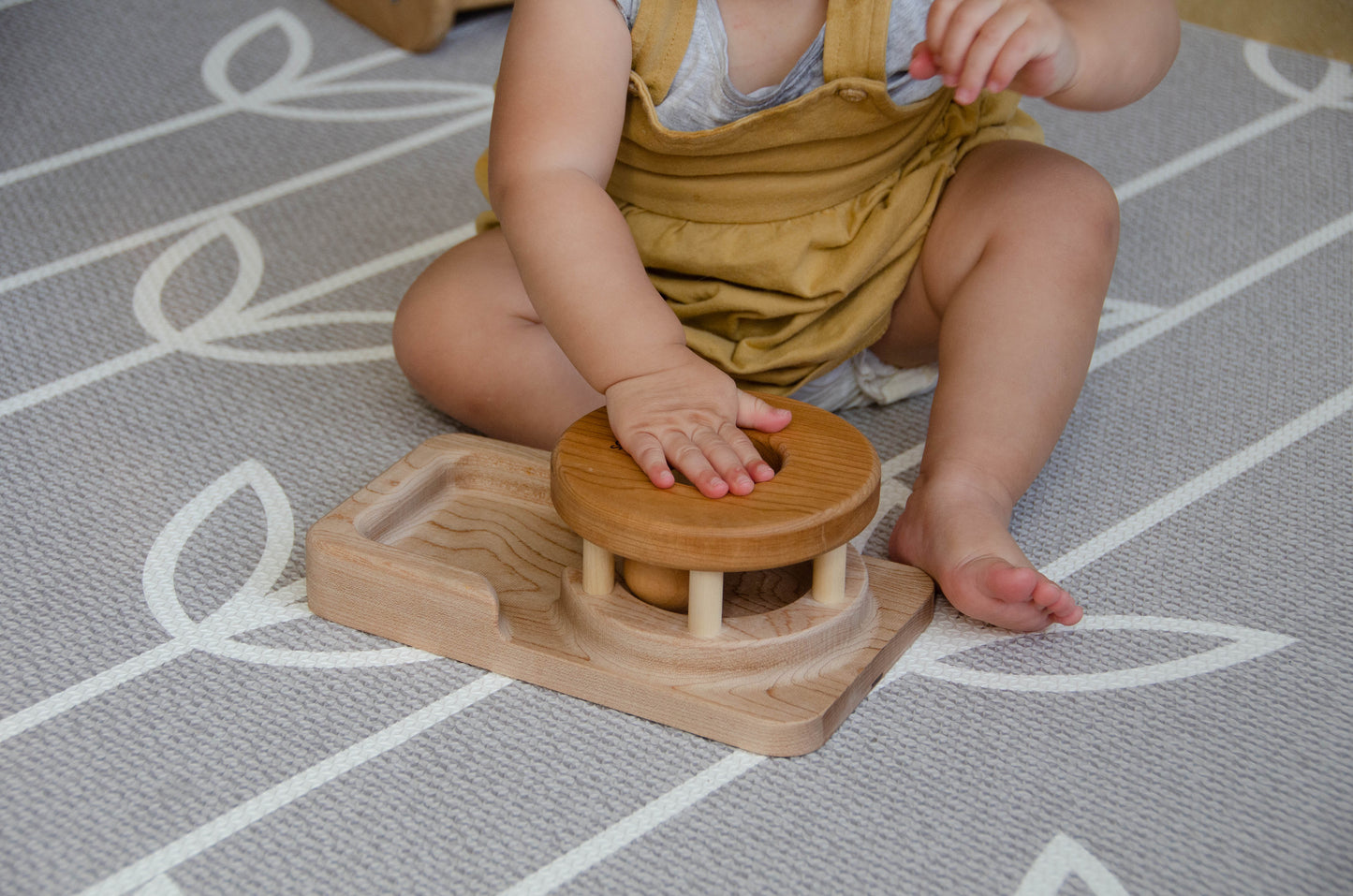 The baby girl is engrossed in play with the Permanence Box, a classic Montessori toy. With great curiosity and excitement, she explores the various compartments, practicing her hand-eye coordination and fine motor skills as she discovers the joy of fitting objects into their designated spaces. This educational and interactive playtime experience helps her develop an understanding of object permanence and spatial relationships, providing a foundation for her cognitive development.