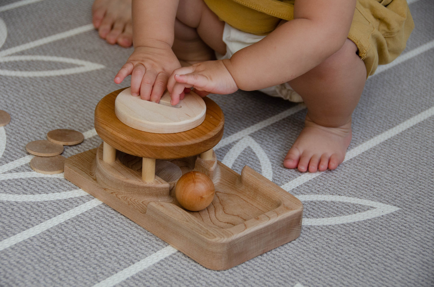 The baby girl is engrossed in play with the Permanence Box, a classic Montessori toy. With great curiosity and excitement, she explores the various compartments, practicing her hand-eye coordination and fine motor skills as she discovers the joy of fitting objects into their designated spaces. This educational and interactive playtime experience helps her develop an understanding of object permanence and spatial relationships, providing a foundation for her cognitive development.