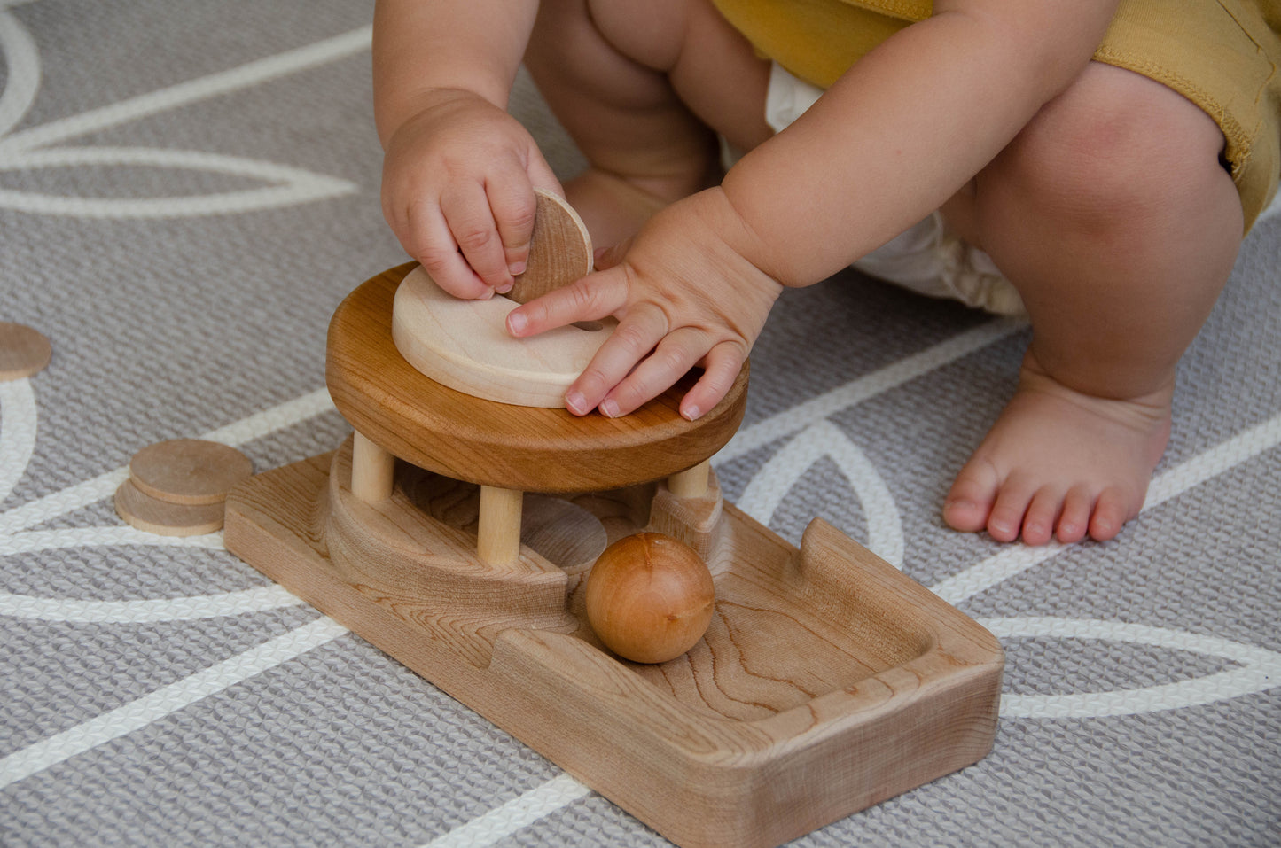 The baby girl is engrossed in play with the Permanence Box, a classic Montessori toy. With great curiosity and excitement, she explores the various compartments, practicing her hand-eye coordination and fine motor skills as she discovers the joy of fitting objects into their designated spaces. This educational and interactive playtime experience helps her develop an understanding of object permanence and spatial relationships, providing a foundation for her cognitive development.