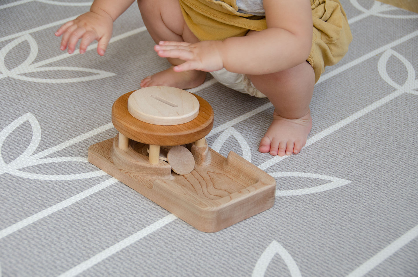 The baby girl is engrossed in play with the Permanence Box, a classic Montessori toy. With great curiosity and excitement, she explores the various compartments, practicing her hand-eye coordination and fine motor skills as she discovers the joy of fitting objects into their designated spaces. This educational and interactive playtime experience helps her develop an understanding of object permanence and spatial relationships, providing a foundation for her cognitive development.