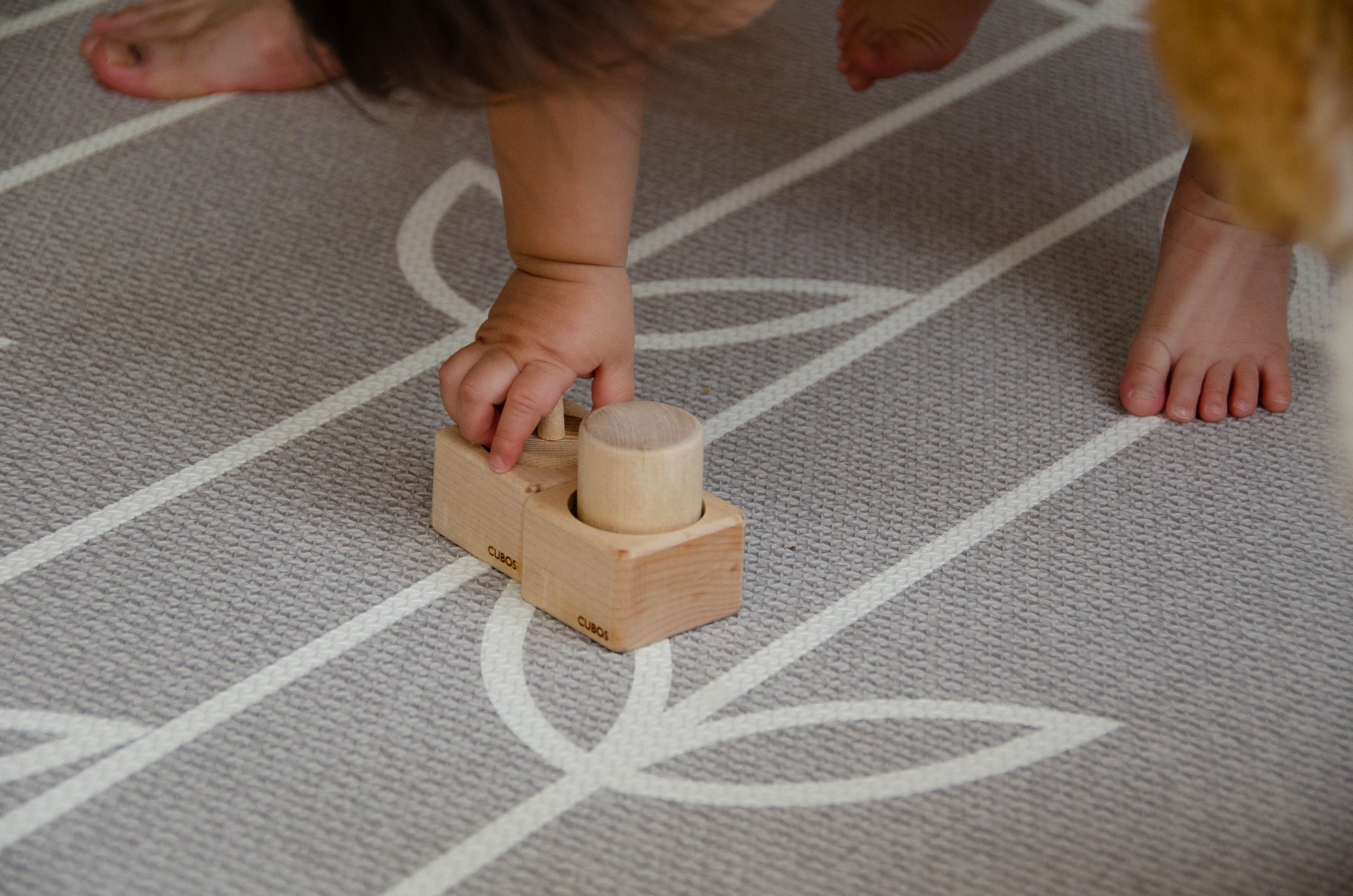 The baby girl is thoroughly enjoying her playtime with Cubos Pincer & Palmer Block. With her tiny hands, she skillfully manipulates the blocks, using the pincer grip to grasp and place them. This interactive and tactile play enhances her fine motor skills, hand-eye coordination, and cognitive development as she explores the different shapes and builds various structures. Her joyful engagement with the educational toy fosters early learning and creativity, making playtime an enriching experience for her.