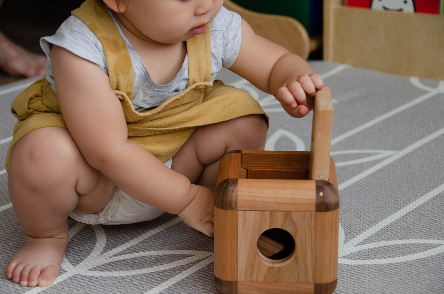 Baby girl happily opens the Cubos Lite, eager to explore and interact with the contents, filled with excitement and curiosity during playtime.