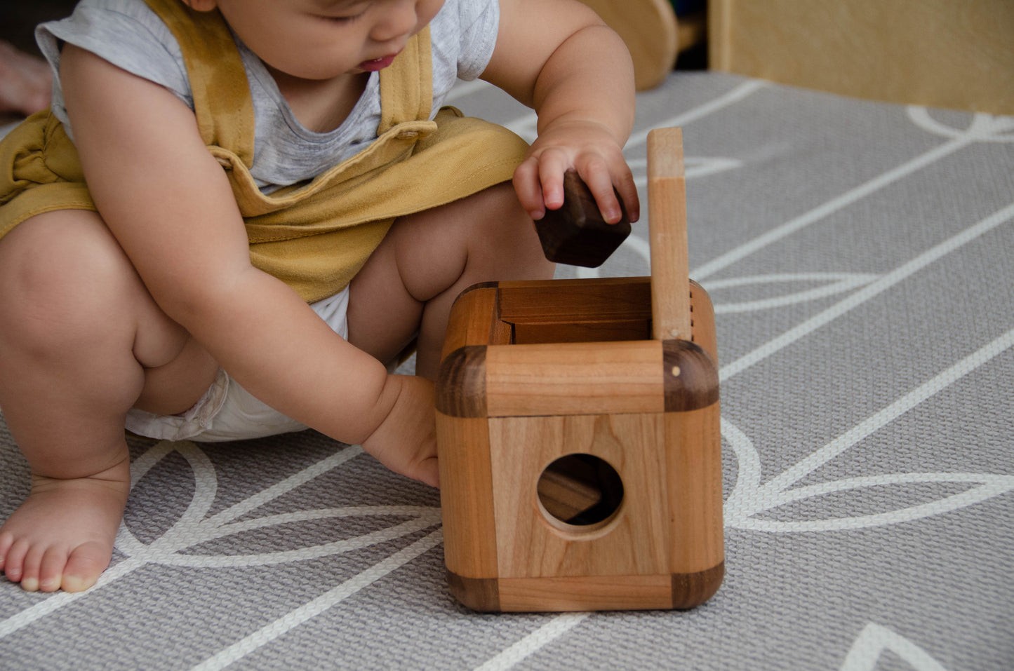 Endearing baby girl carefully putting back the insert pieces into the Cubos Lite, demonstrating her focus and fine motor skills as she tidies up after playtime.