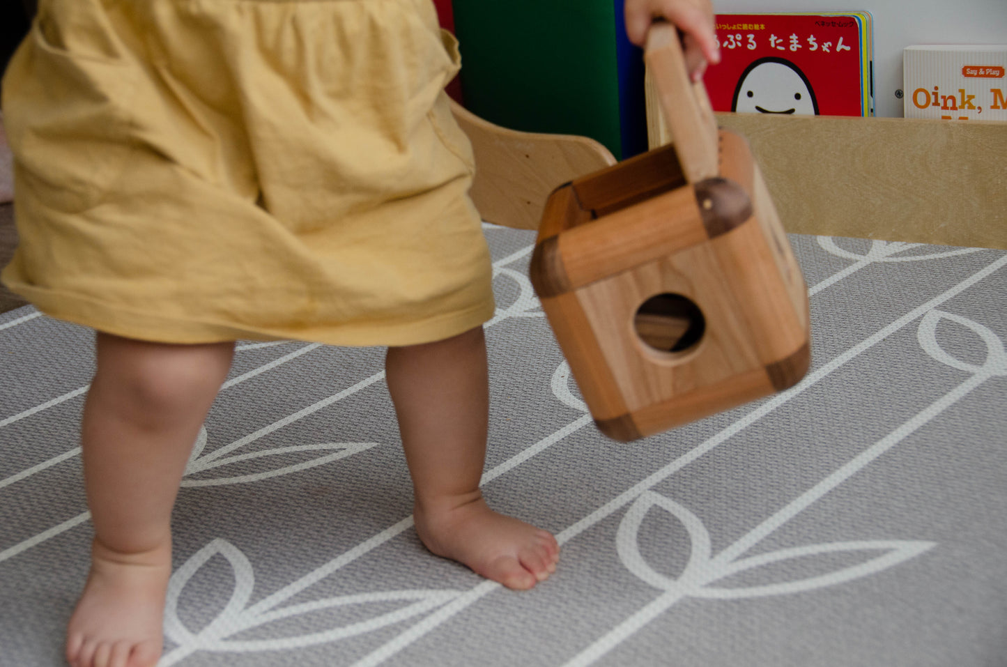 Adorable baby girl happily carrying the Cubos Lite around, embracing the portable and lightweight design, taking her favorite toy with her on her little adventures.