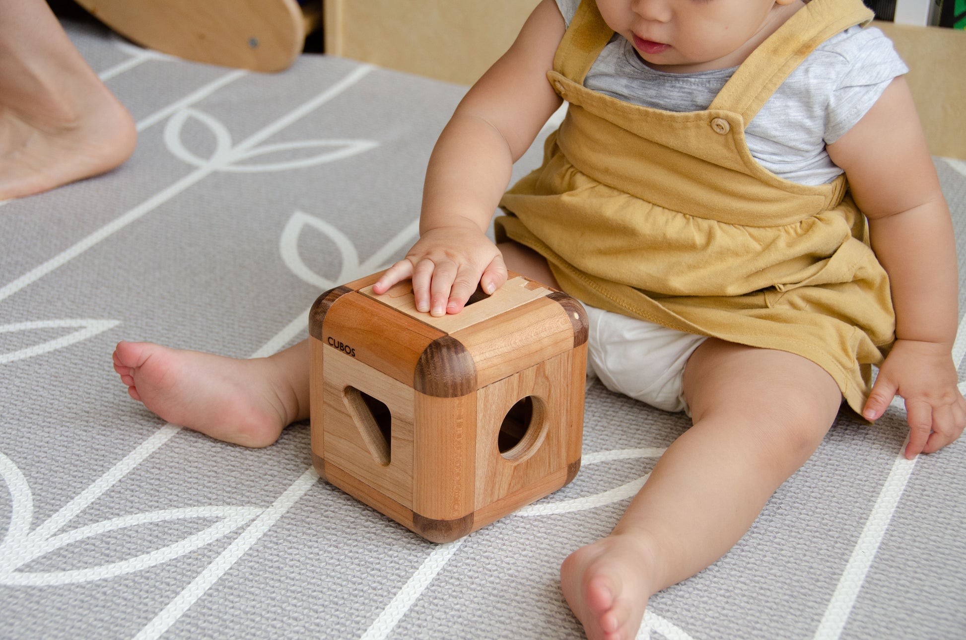 Charming baby girl skillfully inserting the pieces back into the Cubos Lite, demonstrating her growing dexterity and problem-solving abilities, as she enjoys the interactive playtime.
