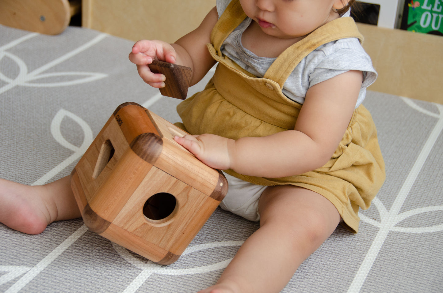 Charming baby girl skillfully inserting the pieces back into the Cubos Lite, demonstrating her growing dexterity and problem-solving abilities, as she enjoys the interactive playtime.