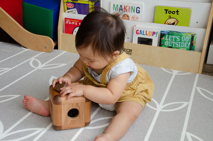 Baby girl gleefully placing the square insert into the Cubos Lite, mastering the art of spatial manipulation and enjoying the satisfying engagement with the interactive toy.