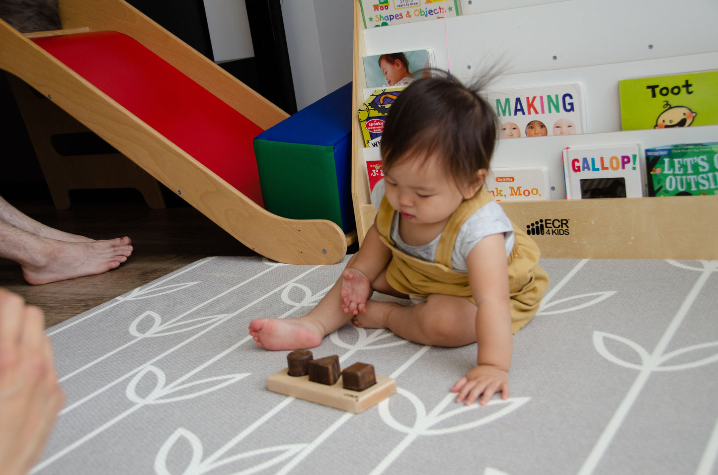 Adorable baby girl happily playing with Cubos Basic, exploring different shape wooden blocks and enjoying the creative possibilities offered by this engaging and educational toy.