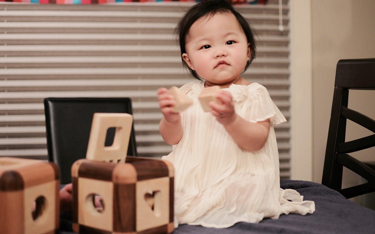 Sweet baby holding the triangle and square pieces of the Cubos Lite set, showcasing their inquisitive nature and early exploration of shapes and textures.