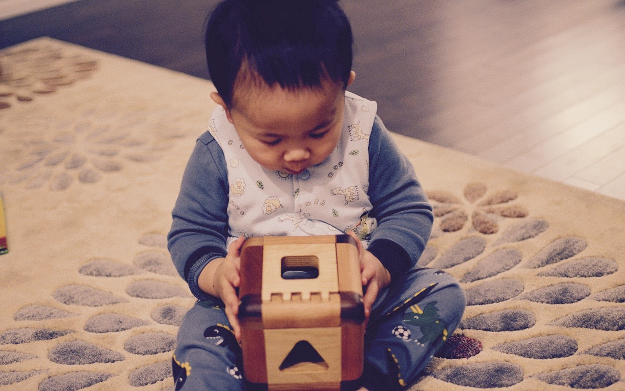 Baby boy captivated by the Cubos Lite, gazing into its contents with wonder and curiosity, ready to embark on a world of imaginative play and learning.