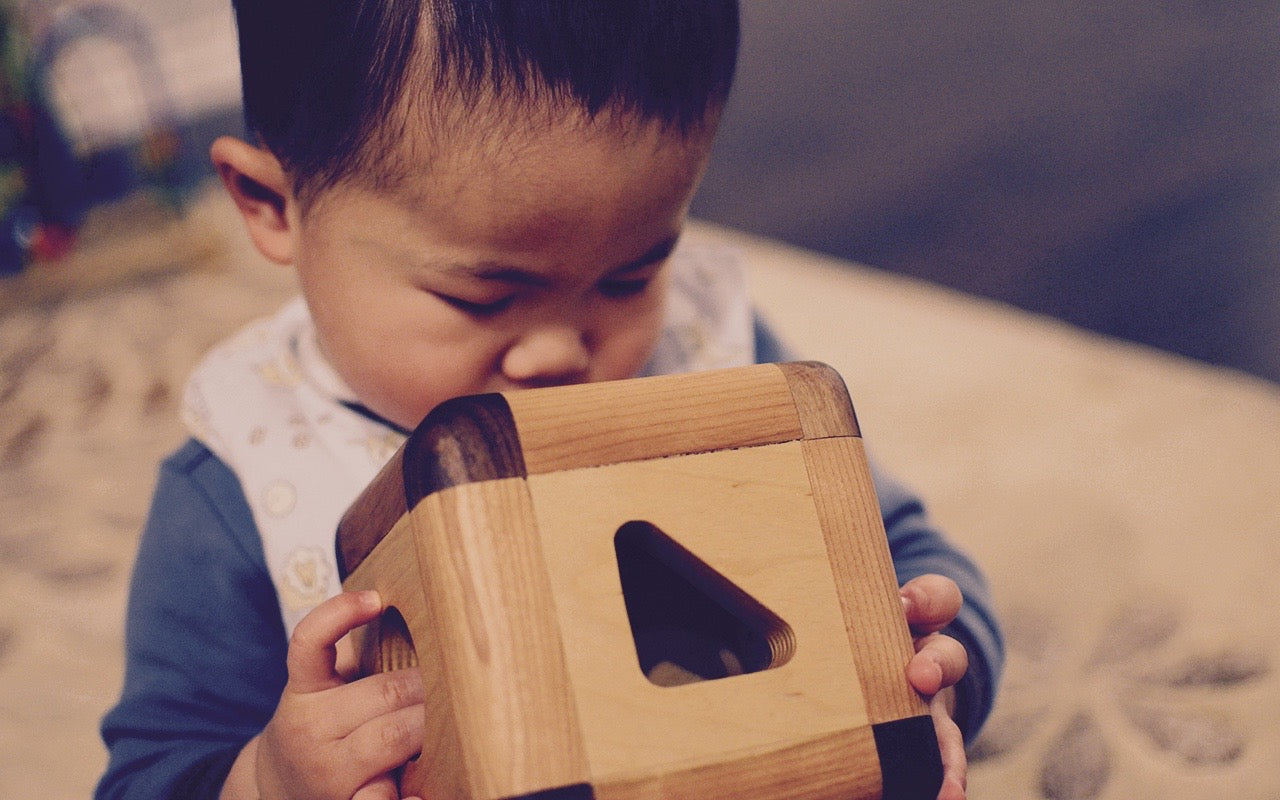 Baby boy captivated by the Cubos Lite, gazing into its contents with wonder and curiosity, ready to embark on a world of imaginative play and learning.