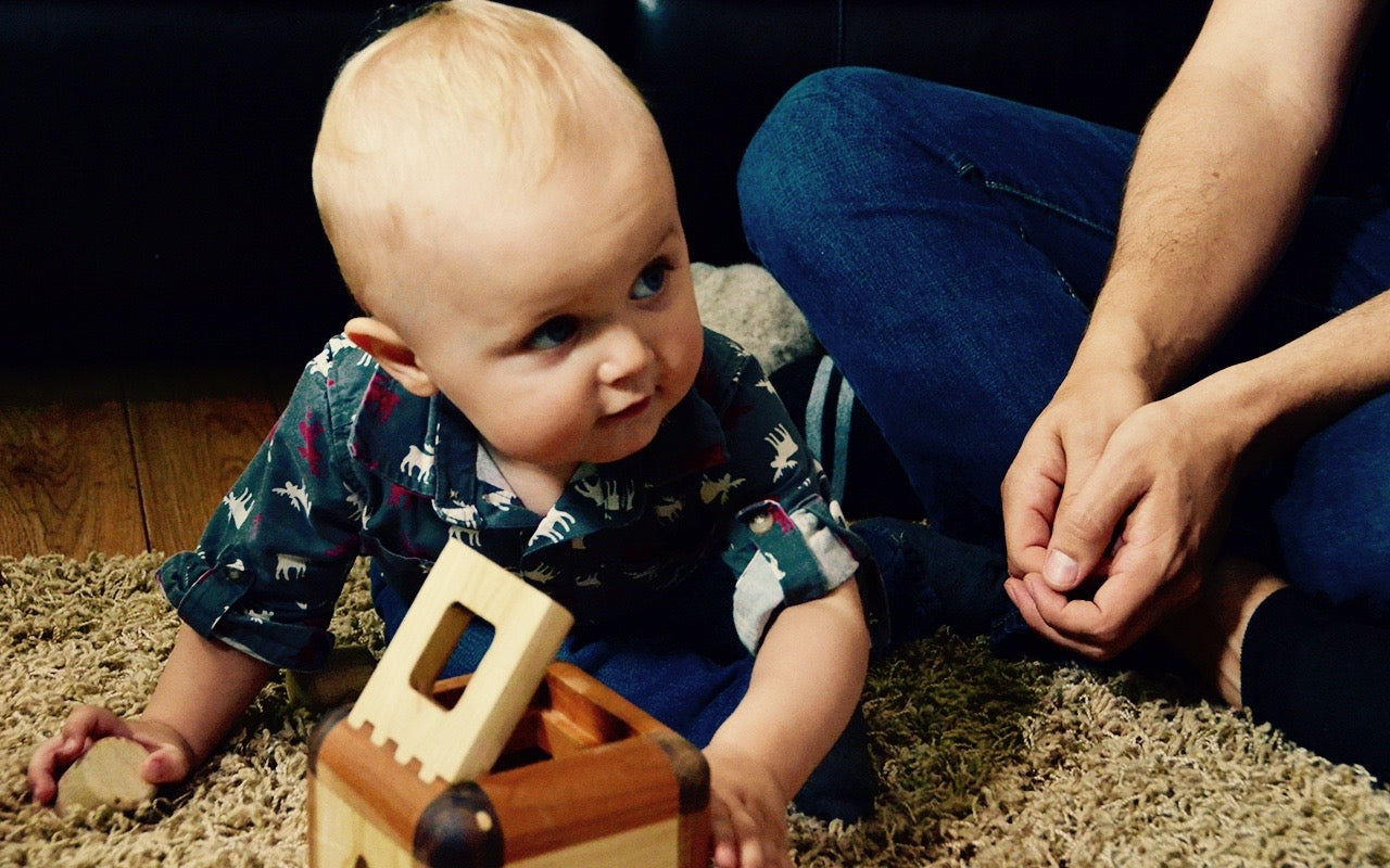 Baby boy captivated by the Cubos Lite, gazing into its contents with wonder and curiosity, ready to embark on a world of imaginative play and learning."