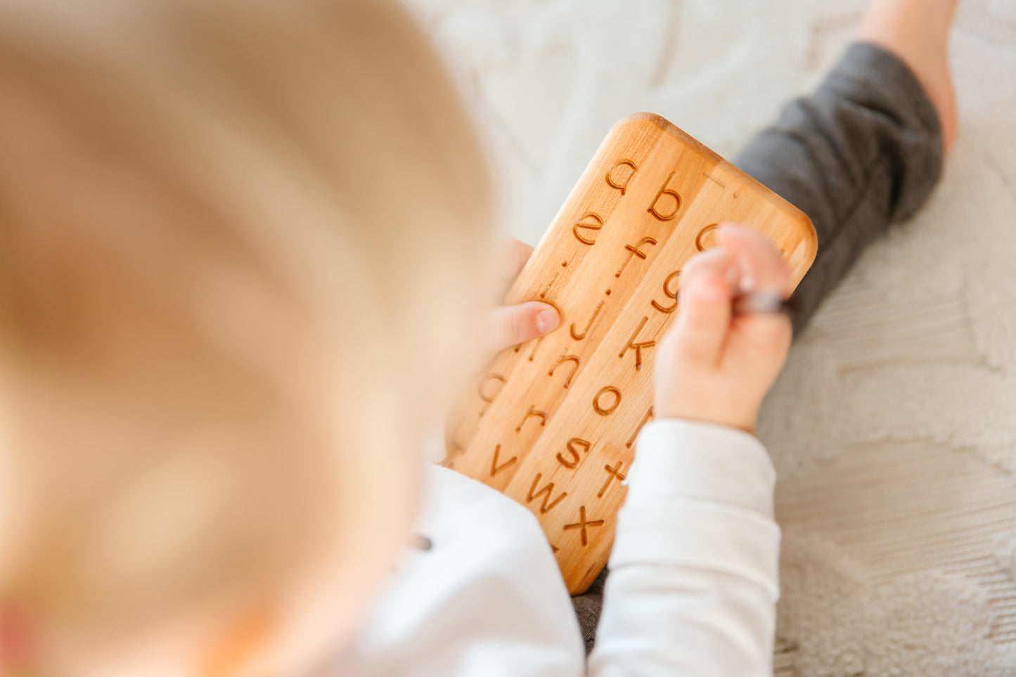 Sweet baby boy thoroughly enjoying the wooden toy iDoddle, using its features to trace and practice writing the ABC. His playtime with this educational and tactile toy fosters early learning and enhances his fine motor skills as he explores the world of letters and creativity.